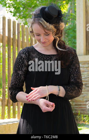 Woman in Black Dress, die versuchen, auf einem Armband Stockfoto