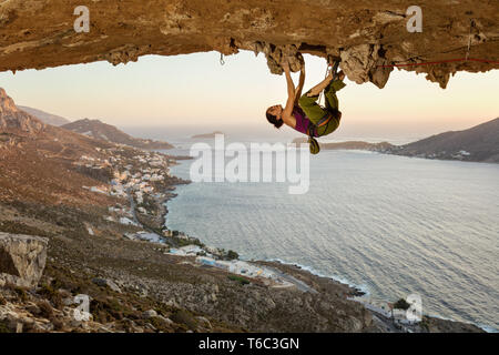 Junge Frau klettern in der Höhle bei Sonnenuntergang der Insel Kalymnos, Griechenland Stockfoto