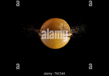 Orange Spritzer ins Wasser auf schwarzem Hintergrund Stockfoto