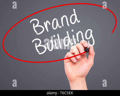 Mann Hand schreiben Marke Gebäude mit schwarzem Marker auf visuelle Bildschirm Stockfoto