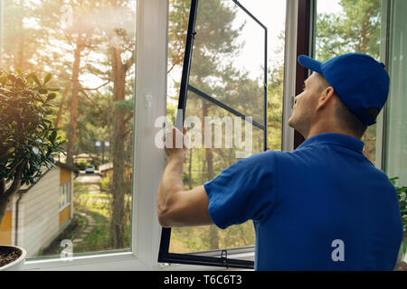 Arbeitnehmer installation Moskitonetz Drahtgitter auf Haus Fenster Stockfoto