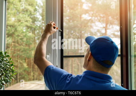 Mann installation Moskitonetz Drahtgitter auf Haus Fenster Stockfoto