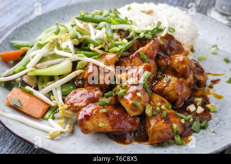 Huhn süß-sauer mit Gemüse und Reis als Close-up auf einer Platte Stockfoto