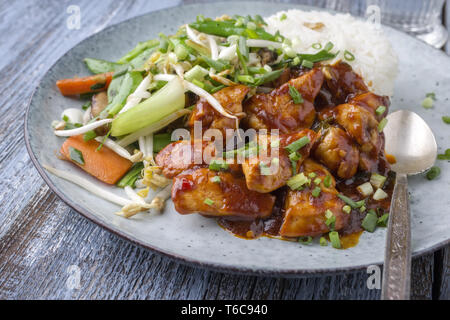 Huhn süß-sauer mit Gemüse und Reis als Close-up auf einer Platte Stockfoto