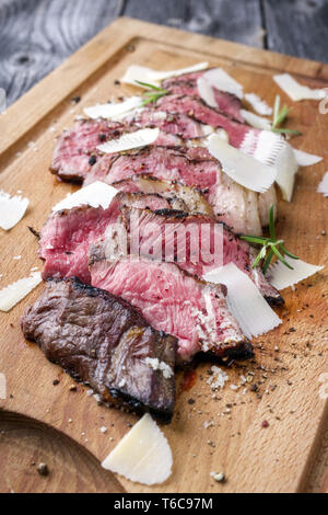 Traditionelle italienische Tagliata Steak mit Parmesan als Close-up auf Schneidebrett Stockfoto