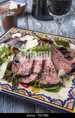 Traditionelle italienische Tagliata di manzo Steak mit Parmesankäse und Salat als Close-up auf einer Platte Stockfoto