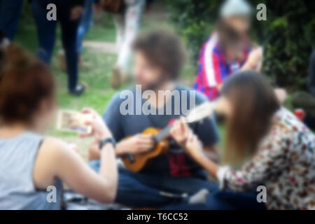 Junge Menschen liegen auf dem Rasen, schickes. Starke Blur, anonyme Menschen auf den Straßen Europas Stockfoto