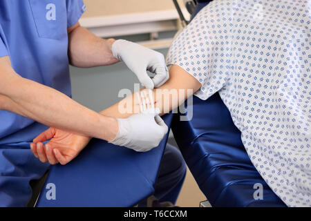 Arzt hilft Patienten mit Wunde am Arm Stockfoto