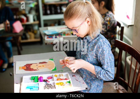 Lächelnd hübsches blondes Mädchen ihre Zeit genießen art Studio. bis Foto schliessen. Sculpting Lektionen. Kleines Mädchen macht ein schönes pportrait. Stockfoto