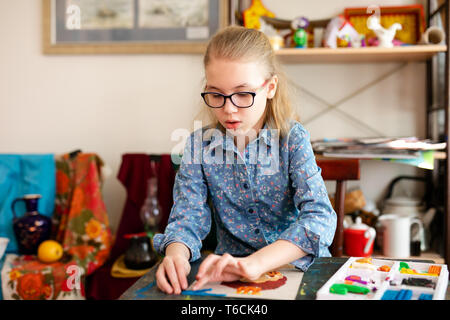 Lächelnd hübsches blondes Mädchen ihre Zeit genießen art Studio. bis Foto schliessen. Sculpting Lektionen. Kleines Mädchen macht ein schönes pportrait. Stockfoto