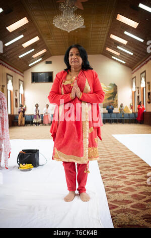 Eine attraktive Frau mittleren Alters Hindu in einem schönen Sari mit ihren Händen in einem Tempel in Jamaica, Queens, New York City umklammerte. Stockfoto