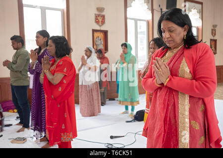 Frauen in einem hinduistischen Tempel beten und meditieren mit geschlossenen Augen und gefalteten Händen. An einem Tempel in Jamaica, Queens, New York City. Stockfoto