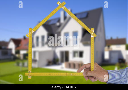 Shell von Haus im Bau mit Zollstock in der Hand von Real estate agent Stockfoto