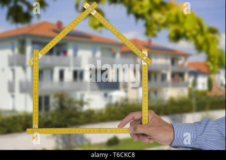 Shell von Haus im Bau mit Zollstock in der Hand von Real estate agent Stockfoto