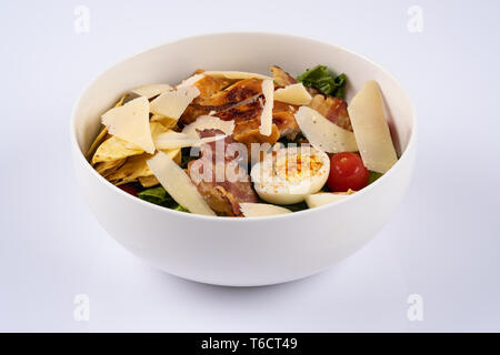 Selektiver Fokus klassische Caesar Salat mit gerösteten Chiken, Speck, Wachteleier, Salatblätter, Chips, Parmesan, Kirschtomaten auf die weiße runde Pla Stockfoto