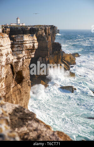 Felsen und Wellen surfen im Meer in der Nähe von Cabo Carvoeiro, Peniche Halbinsel mit dem Leuchtturm im Hintergrund, Portugal Stockfoto