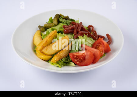 Gegrillte Würstchen, gebackene Kartoffeln und Gemüse. Salat mit Würstchen, Kartoffeln, Tomaten Gurken Stockfoto