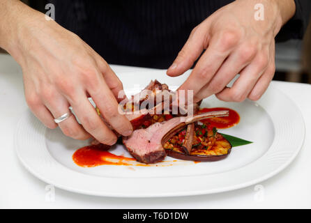 Koch macht Fleischgericht auf gewerbliche Küche Stockfoto