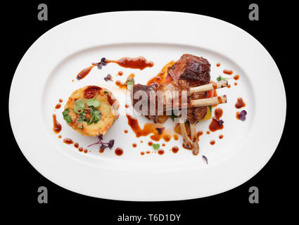 Gegrillter Lammrücken in ovalen Platte auf schwarzem Hintergrund Stockfoto