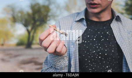 Die Person, die das Rauchen von Marihuana gemeinsame im Freien. Cannabis joint in der Hand Stockfoto