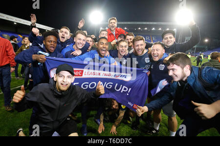 Spieler begraben und Fans feiern Förderung nach dem Schlusspfiff während der Sky Bet Liga Match in Prenton Park, werben. Stockfoto