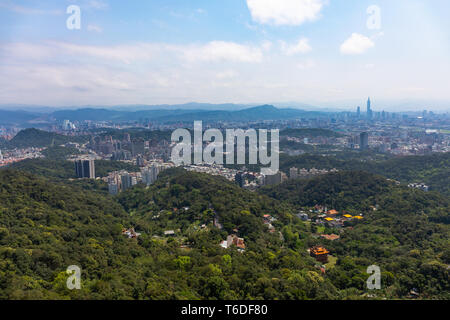 Taipei, Taiwan mit Vororten und grüne Hügel mit Xinyi Business District in weitem Abstand wie den städtischen Raum greift in die Umwelt. Stockfoto