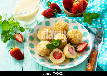 Quark Knödel mit frischen Erdbeeren, serviert mit Sauer - Honig Sauce, köstlichen Sommer Dessert auf der Küche Holztisch. Stockfoto