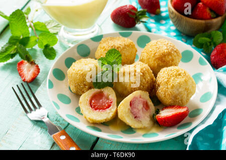 Quark Knödel mit frischen Erdbeeren, serviert mit Sauer - Honig Sauce, köstlichen Sommer Dessert auf der Küche Holztisch. Stockfoto