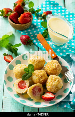 Quark Knödel mit frischen Erdbeeren, serviert mit Sauer - Honig Sauce, köstlichen Sommer Dessert auf der Küche Holztisch. Stockfoto