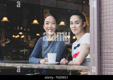 Blick durch Fenster von Mutter und Tochter sitzen im Café mit Kaffee Tasse. Stockfoto