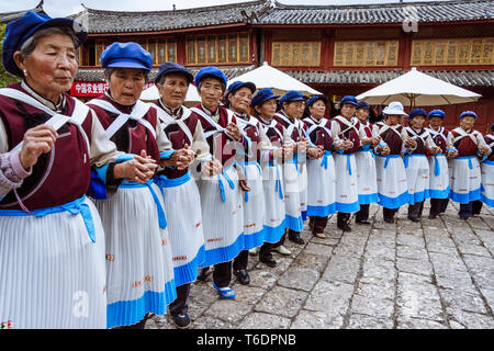 Lijiang, Yunnan, China: eine große Gruppe von Naxi Frauen in den regionalen Kostüm Tanz in einer Reihe am Alten Markt in der Altstadt von Lijiang, Stockfoto