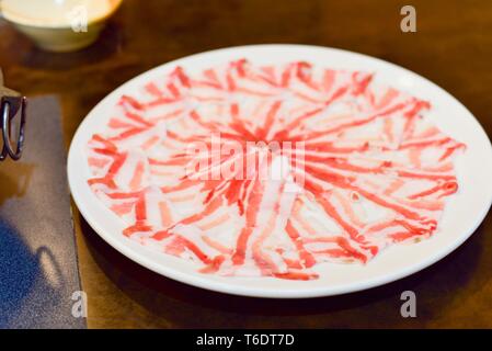 Rohes Schweinefleisch Kurobuta Slices auf weiße Platte für Shabu Shabu Stockfoto