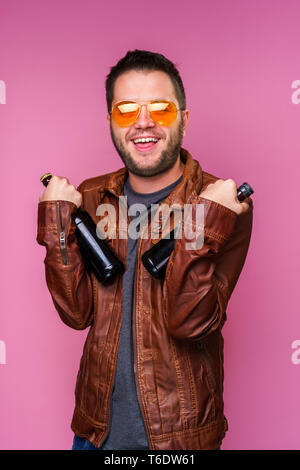 Fotos von lächelnden Brunet in orange Gläser und Lederjacke mit zwei Flaschen in der Hand Stockfoto