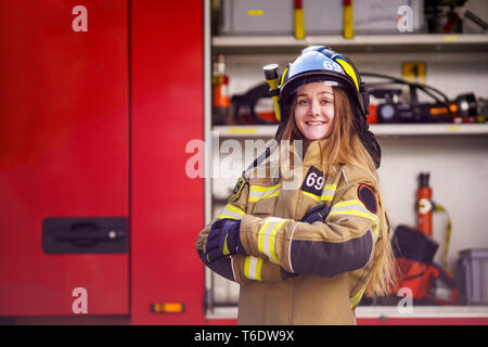 Foto von Frau Feuerwehrmann in Helm mit gekreuzten Armen stehen in der Nähe von Feuer Lkw Stockfoto