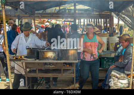 Ein Mann serviert seinen Gästen an Seine beiläufige typische Speisen vom Grill Stall, während des traditionellen lokalen Markt von Villa de Leyva, Kolumbien. Stockfoto