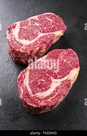 Zwei Rohmaterial trocken im Alter von Kobe Entrecote Steaks als Close-up auf einer Schiefertafel Stockfoto