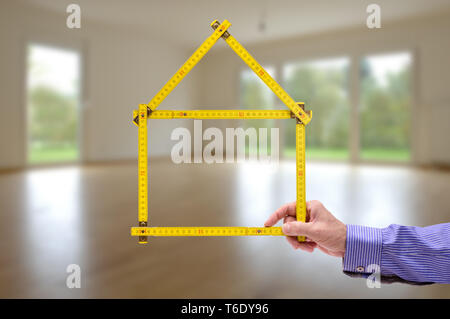 Shell von Haus im Bau mit Zollstock in der Hand von Real estate agent Stockfoto