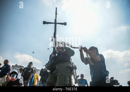 Ein anti Regierung Soldat mit Maschinengewehr die Stelle für den Kampf bereit. Venezolanischen Militärs, die Unterstützung der venezolanischen Opposition leader Juan Guaido sind auf die Strasse mit ihren Waffen zusammen mit der Regierung die Demonstranten in einem Militärputsch gegen die sozialistische Regierung unter der Führung von Präsident Nicolas Maduro. Stockfoto