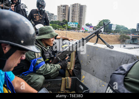 Ein anti Regierung Soldat mit Maschinengewehr die Stelle für den Kampf bereit. Venezolanischen Militärs, die Unterstützung der venezolanischen Opposition leader Juan Guaido sind auf die Strasse mit ihren Waffen zusammen mit der Regierung die Demonstranten in einem Militärputsch gegen die sozialistische Regierung unter der Führung von Präsident Nicolas Maduro. Stockfoto