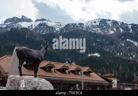 Eine Bronzestatue einer Kuh suchen bis zu den Bergen in Canazei Square Stockfoto