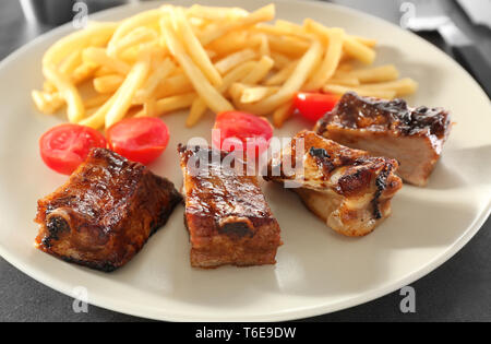 Köstliche gegrillte Rippen und Pommes frites auf Platte, Nahaufnahme Stockfoto