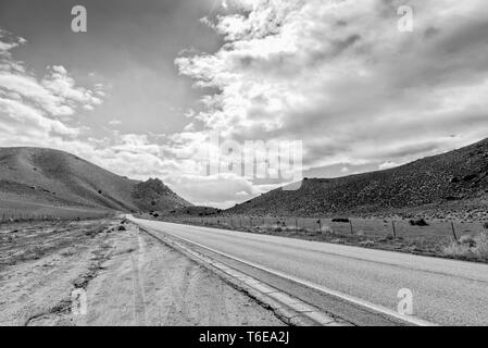 Ziehen Sie am Straßenrand an der County Road suchen in Bergen unter Himmel mit flauschigen weissen Wolken. Schwarz und Weiß. Stockfoto