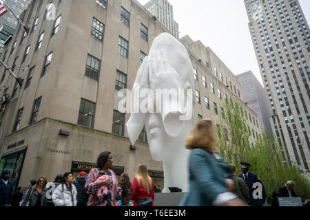 Besucher Pass â € oeBehind der Wallsâ € 2019 von der Künstlerin Juame Plensa am Kopf der Kanal Gärten im Rockefeller Center in New York am Tag der Eröffnung der Frieze Skulptur Installation am Donnerstag, den 25. April 2019. Werke von 14 Künstlern dot das Rockefeller Center Landschaft als Zentrum ist Gastgeber für eine Galerie der Künstler aus New York die Frieze Art Fair, auf Anzeige bis 28. Juni. (Â© Richard B. Levine) Stockfoto