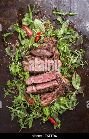 Traditionelle italienische Tagliata di manzo mit Salat und Tomaten als Close-up auf einem alten rostigen Blech Stockfoto