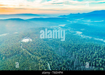 Schönen Sonnenuntergang über Berge und Wälder mit Straße durch - Luftbild Stockfoto