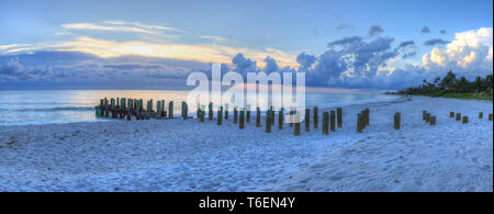 Sonnenuntergang über alte Pier am Meer am Strand von Naples Stockfoto