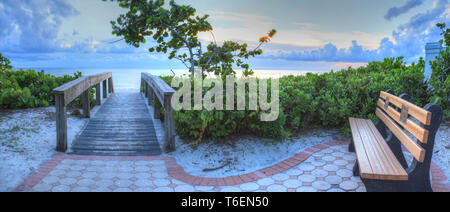 Sitzbank mit Blick auf einen Holzsteg auf Neapel Strand bei Sonnenuntergang Stockfoto