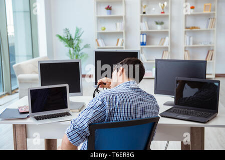 Unternehmer sitzen vor vielen Bildschirmen Stockfoto