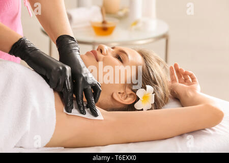 Frau mit Verfahren der Haarentfernung mit Wachs im Salon Stockfoto