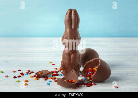 Schokolade Osterhasen, Eier und Streuseln auf hölzernen Tisch Stockfoto